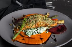 A beautifully plated salmon dish with vibrant vegetables and sauce, perfect for a gourmet dining experience.