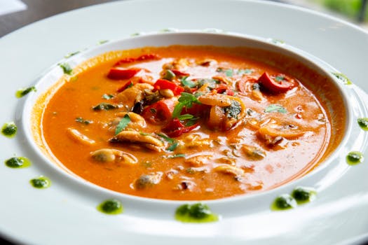 Hearty tomato seafood soup garnished with fresh herbs and peppers, bursting with flavor.