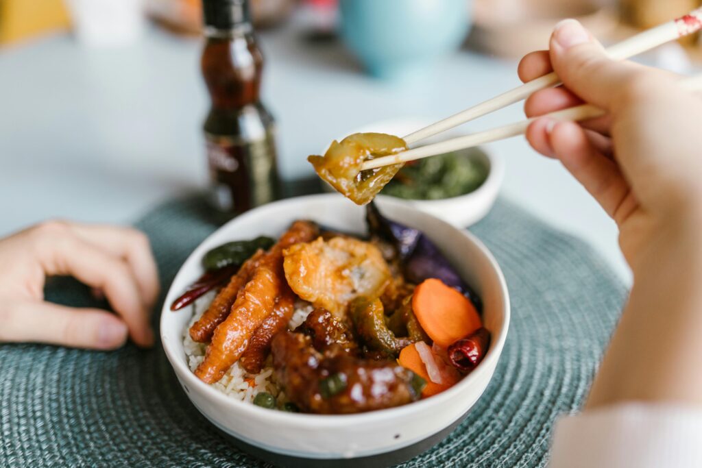 Delicious Asian dish served in a bowl with chopsticks, featuring a variety of vegetables and sauce.