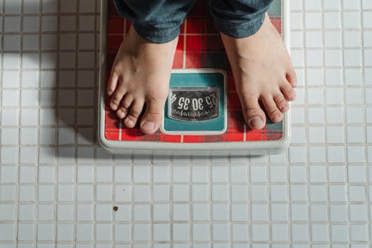 pexels-photo-4474052-4474052 From above crop anonymous barefoot child in jeans standing on weigh scales on tiled floor of bathroom
