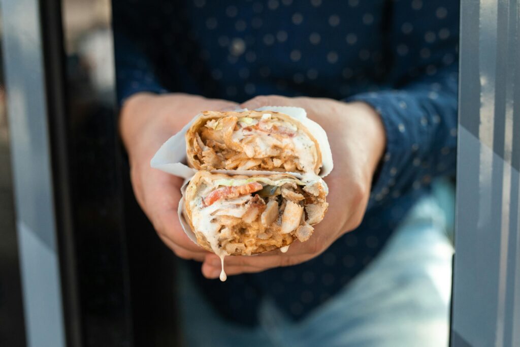 pexels-photo-5779423-5779423 Delicious chicken shawarma held by hand, wrapped with fresh ingredients.