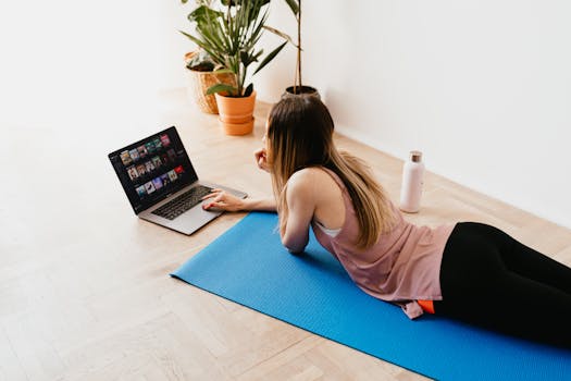 pexels-photo-4498359-4498359 A young woman lying on a yoga mat, browsing on her laptop, enjoying leisure time indoors.